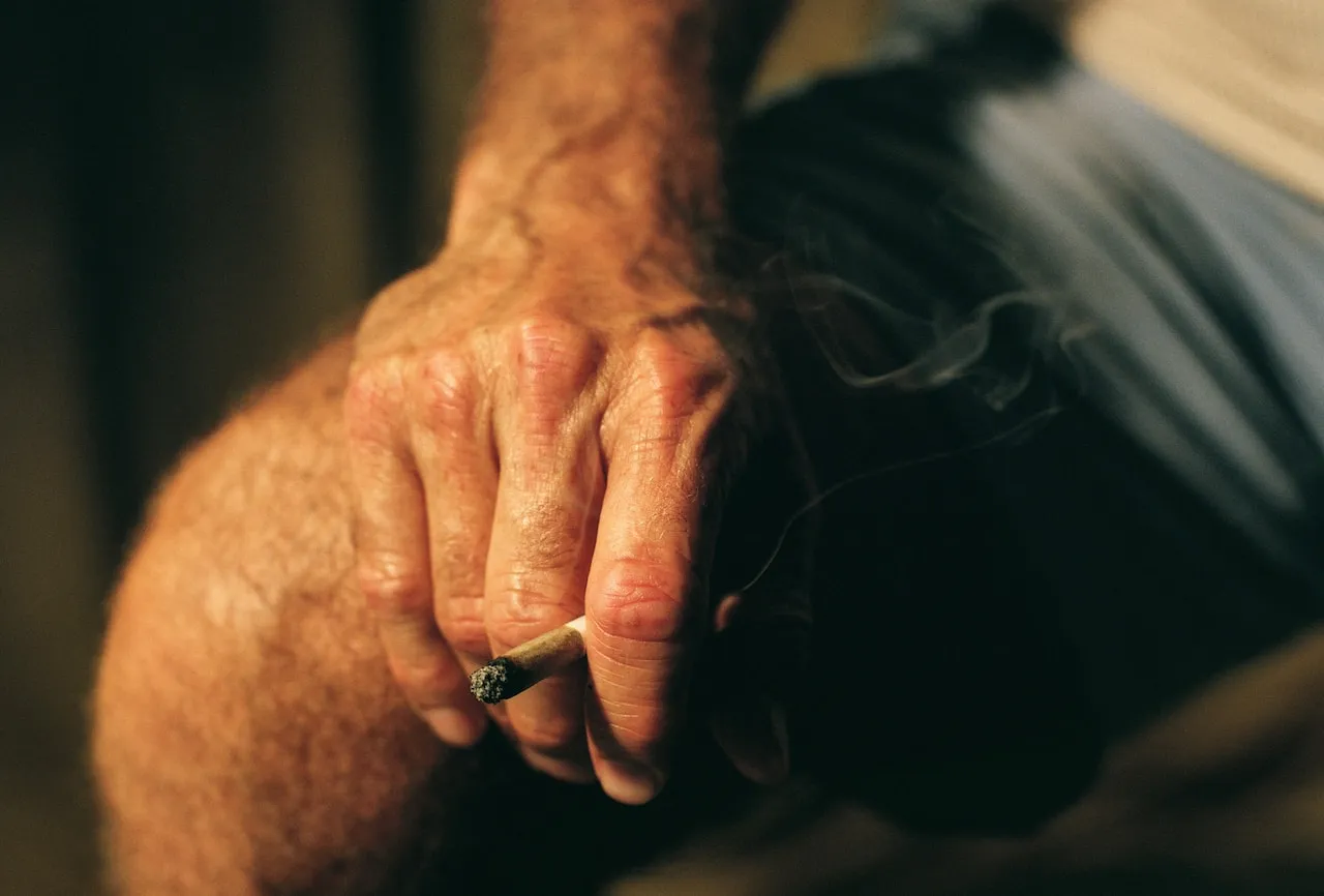 Hand holding a burning cigarette
