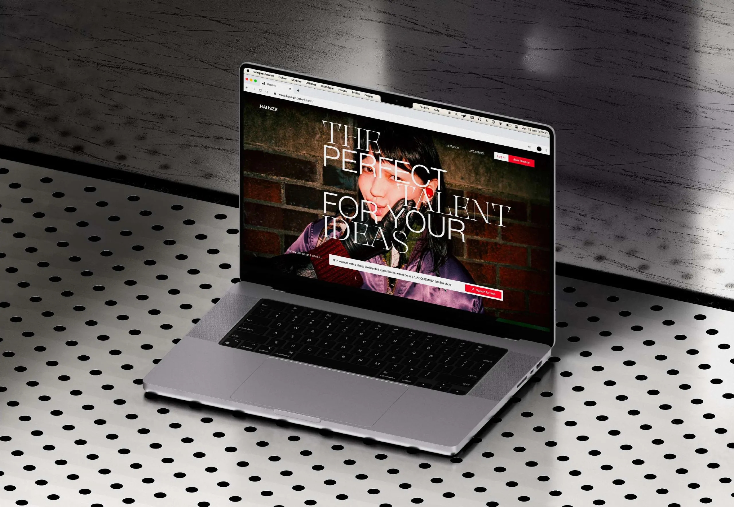 MacBook Pro mockup on perforated metal, the HAUSZE home page on screen