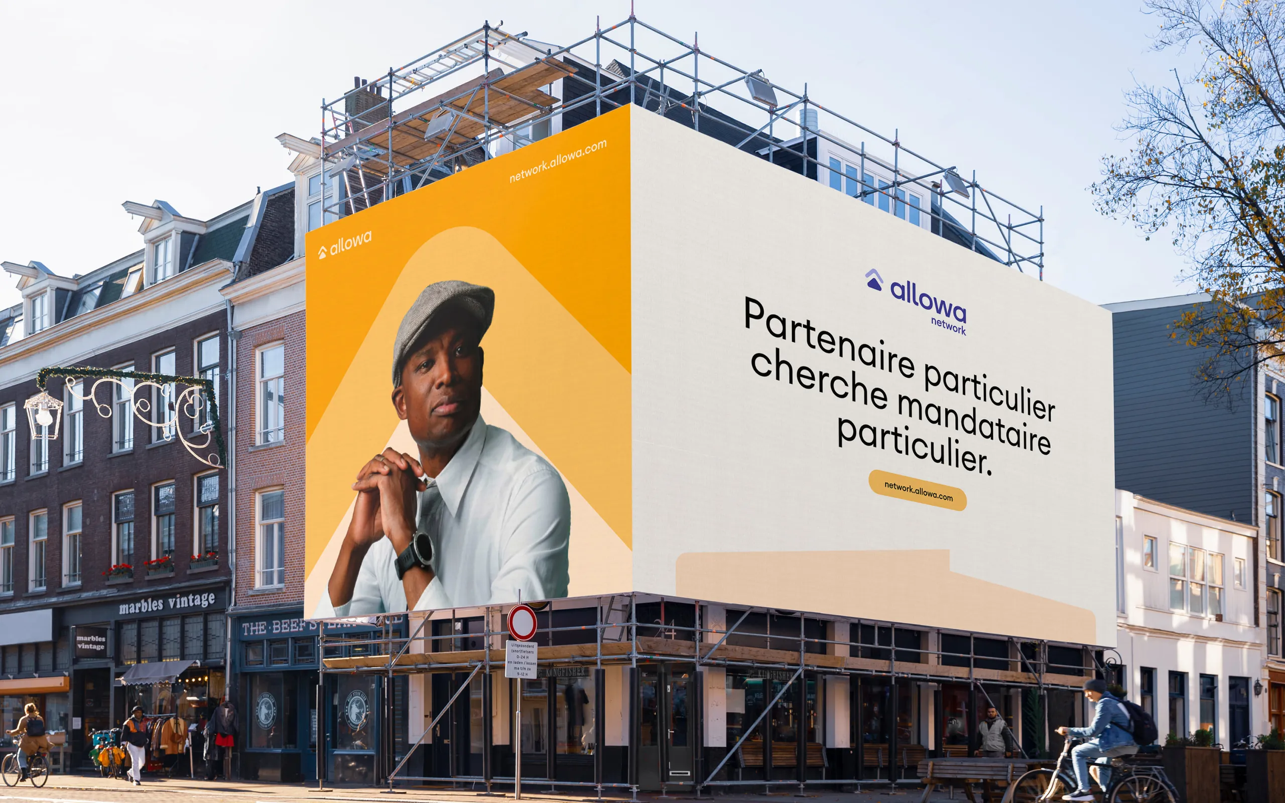 Allowa wall poster on a scaffolded façade, reading “Partenaire particulier cherche mandataire particulier.”
