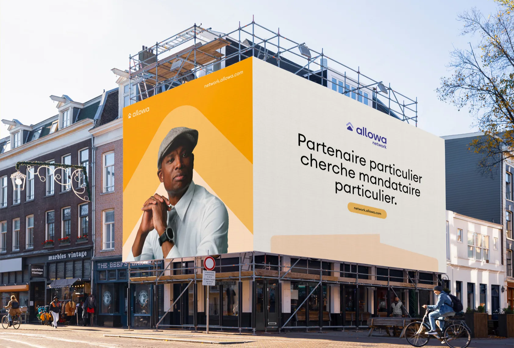 Allowa wall poster on a scaffolded façade, reading “Partenaire particulier cherche mandataire particulier.”