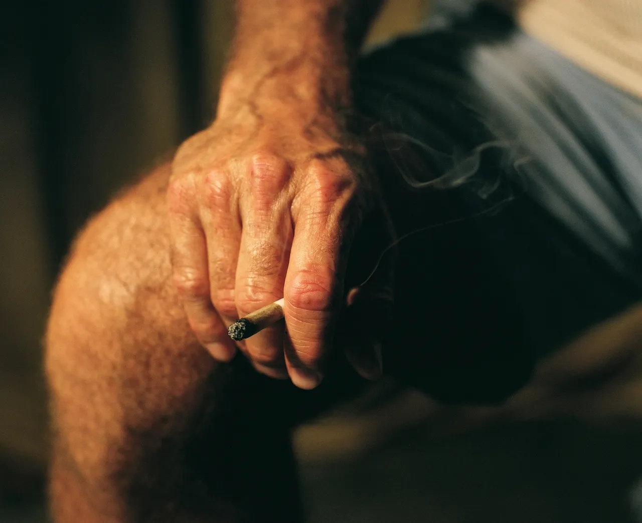 Hand holding a burning cigarette
